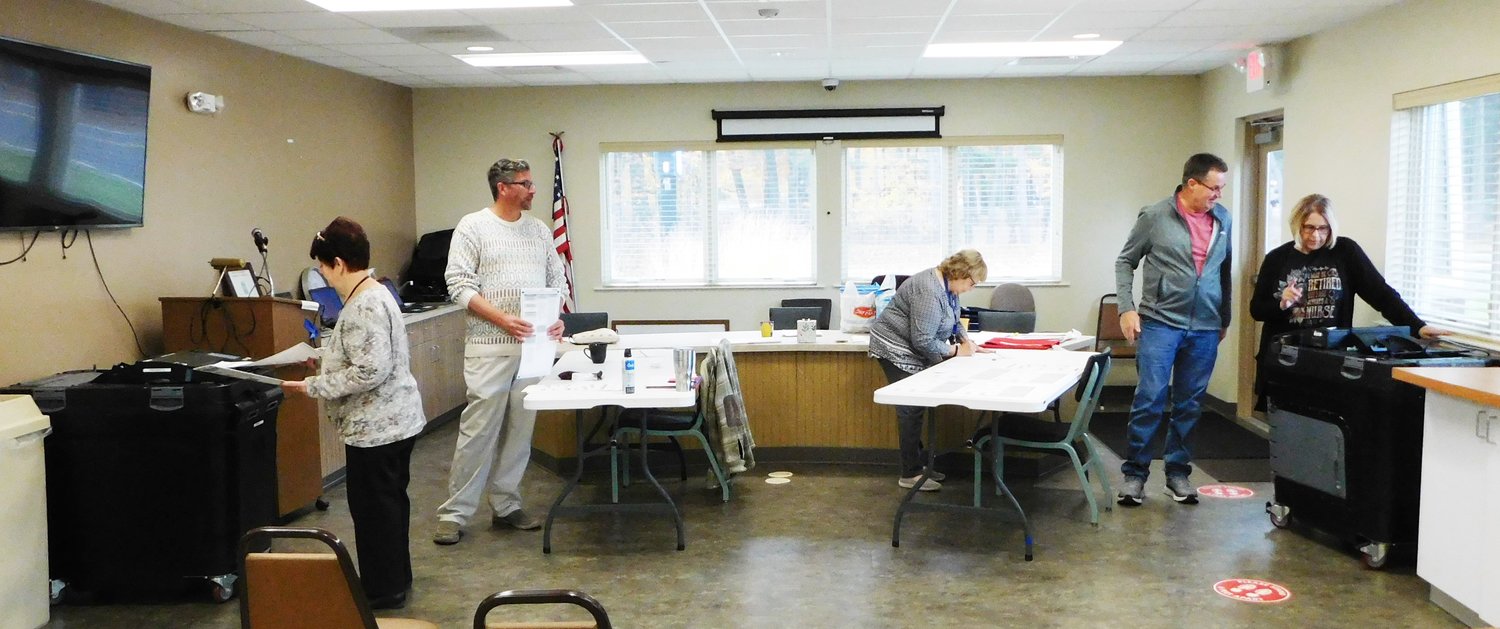 New election inspector Rachelle Burk, left, and Deb Hoyt, Hayes Township clerk, watch on as Ernie Teall, precinct chairperson, clears overflowing ballots from the tabulator’s bin.